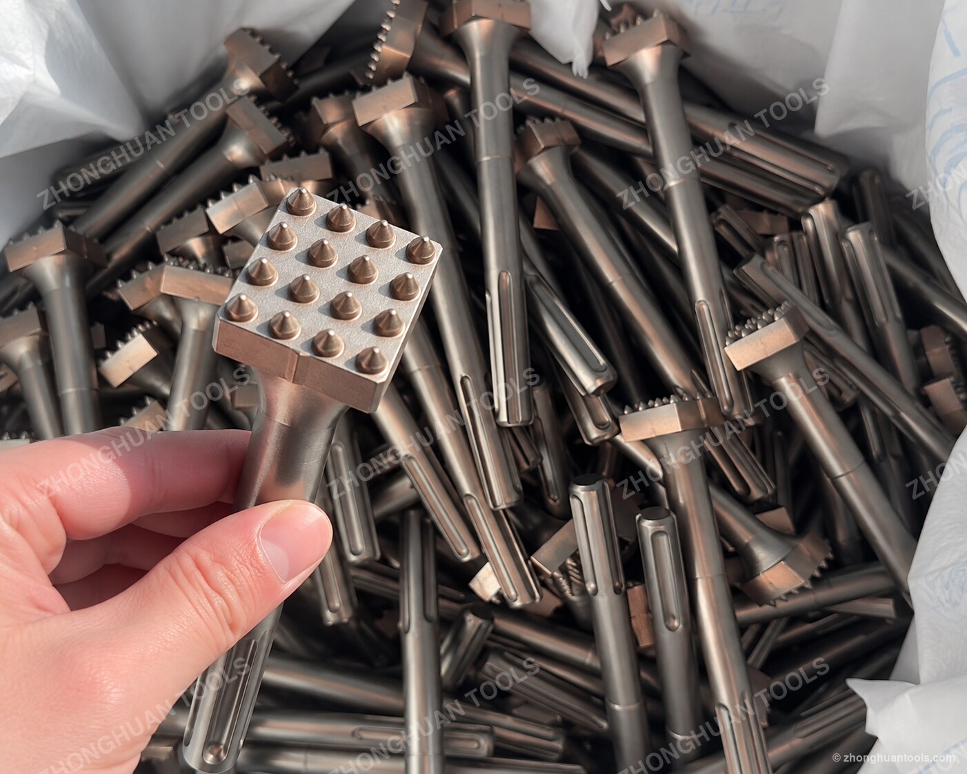 Ein fertiger quadratischer Hartmetall-Pin-Kopf, aus der Charge hochgehalten, Pin-Raster sichtbar