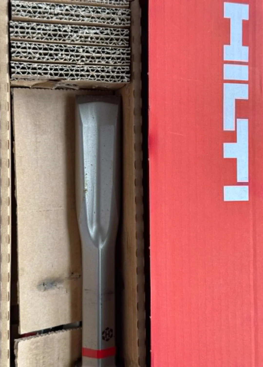 Extrémité plate du Hilti TE-HX FM 40 calée dans du carton à côté de la boîte rouge