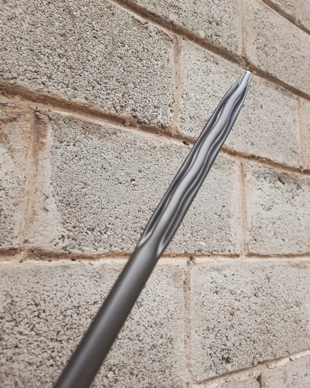 Supplied close-up of wave-shaped raised sections and relief valleys converging toward a pointed chisel tip